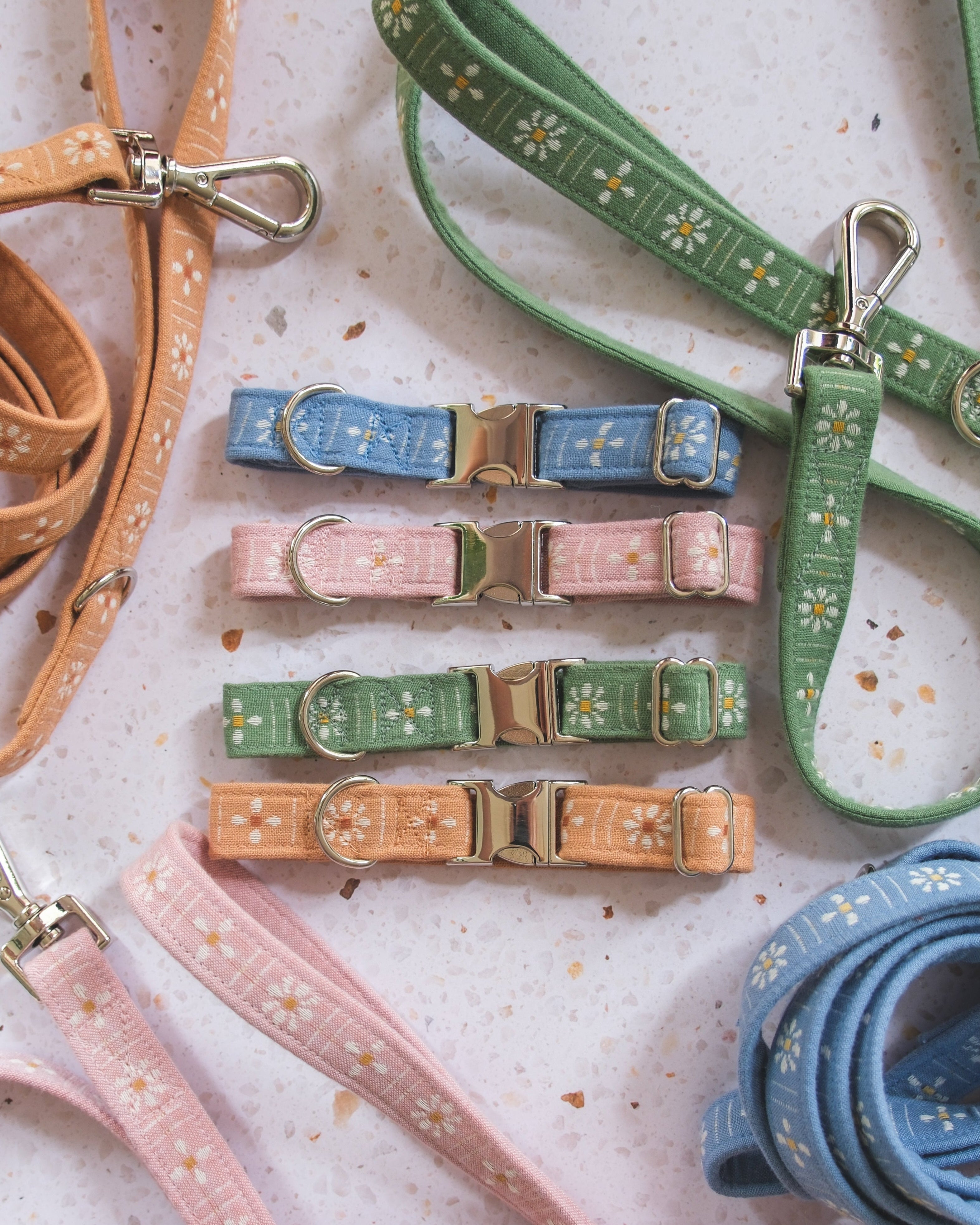 Collection of dog collars and leashes in various colors on a textured surface