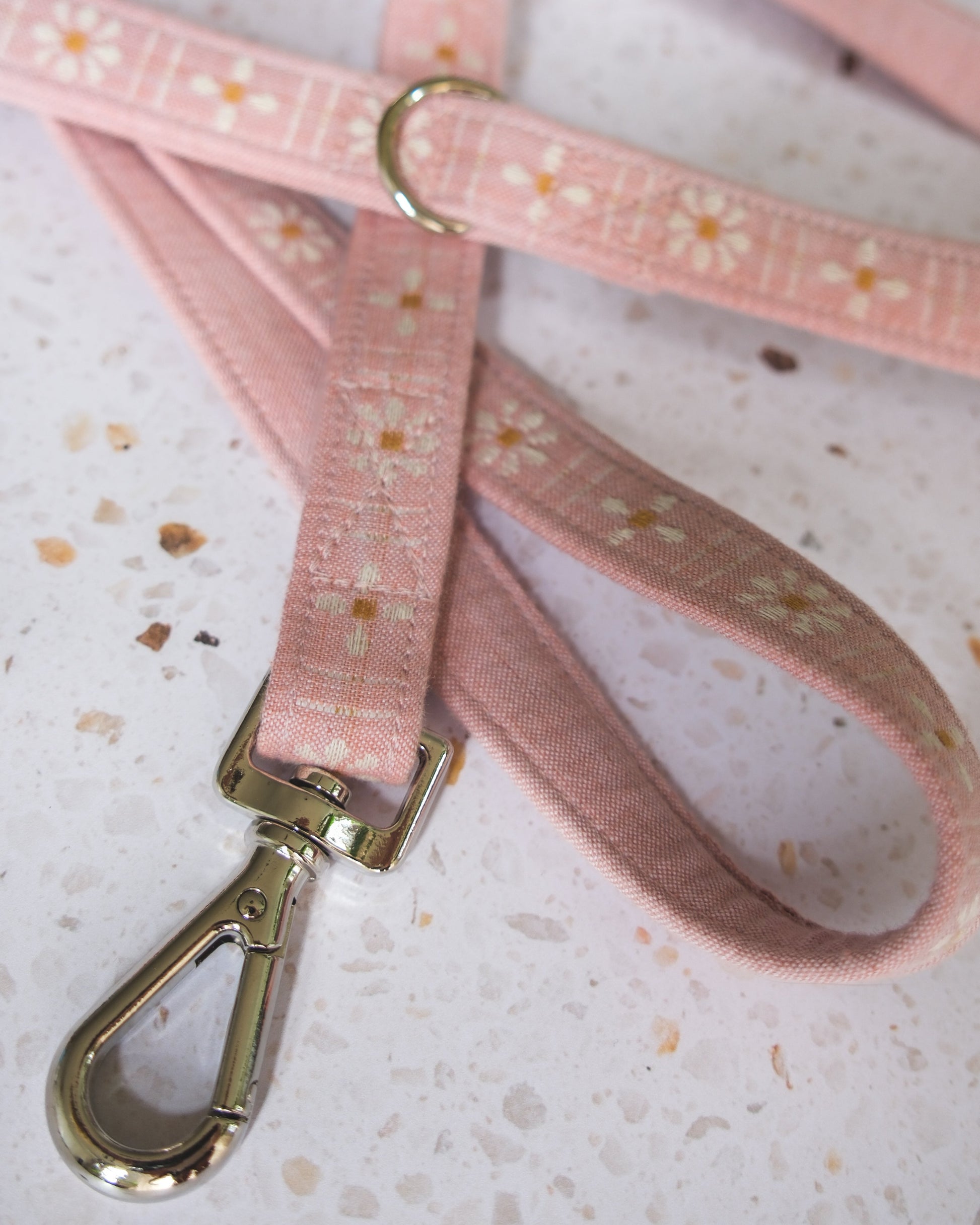 Pink dog leash with floral pattern and metal clip on a light background