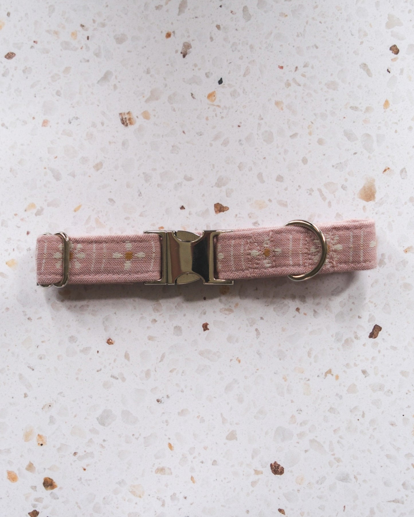 Pink dog collar with a metal buckle on a light gray surface