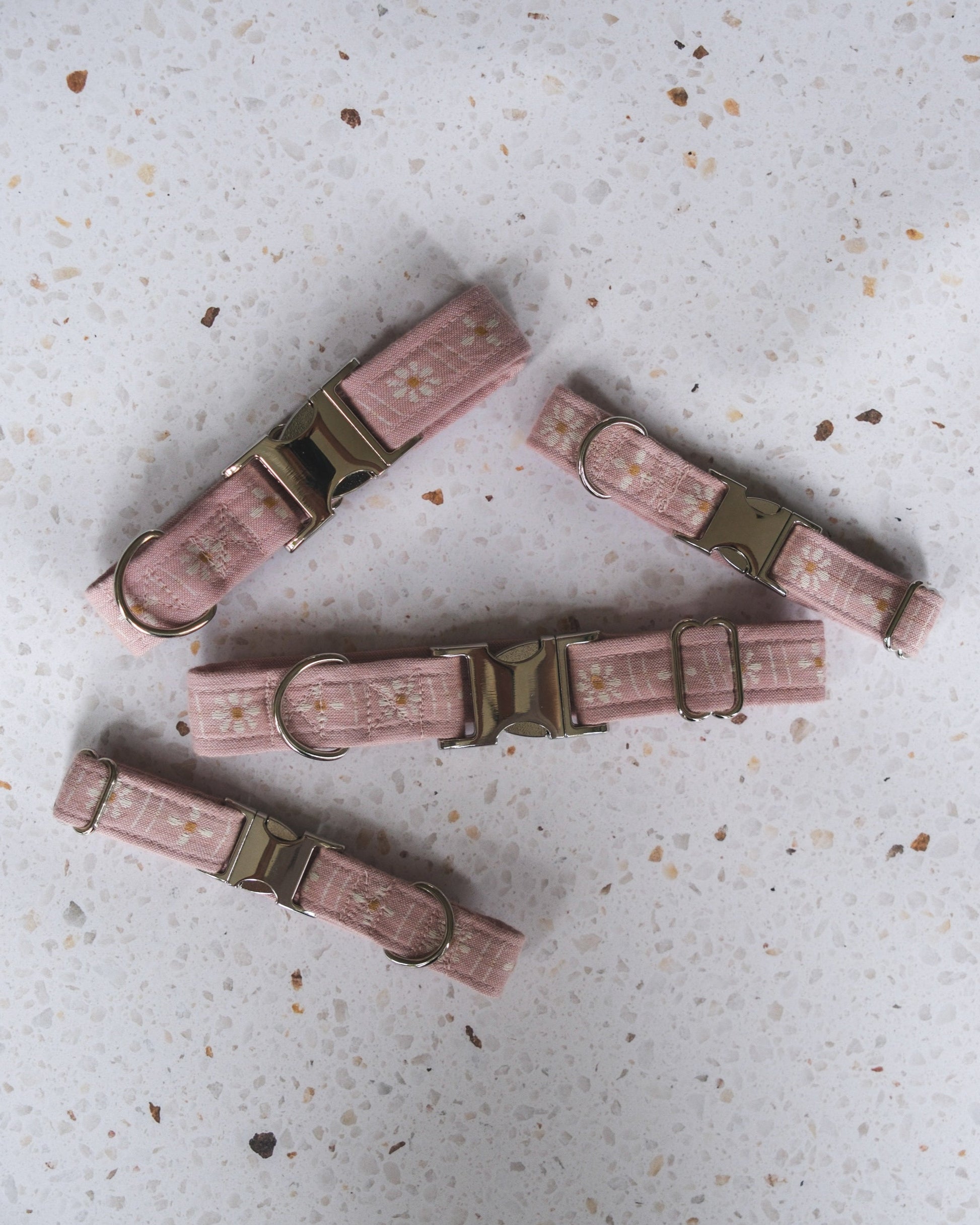 Pink dog collars with metal buckles on a textured surface
