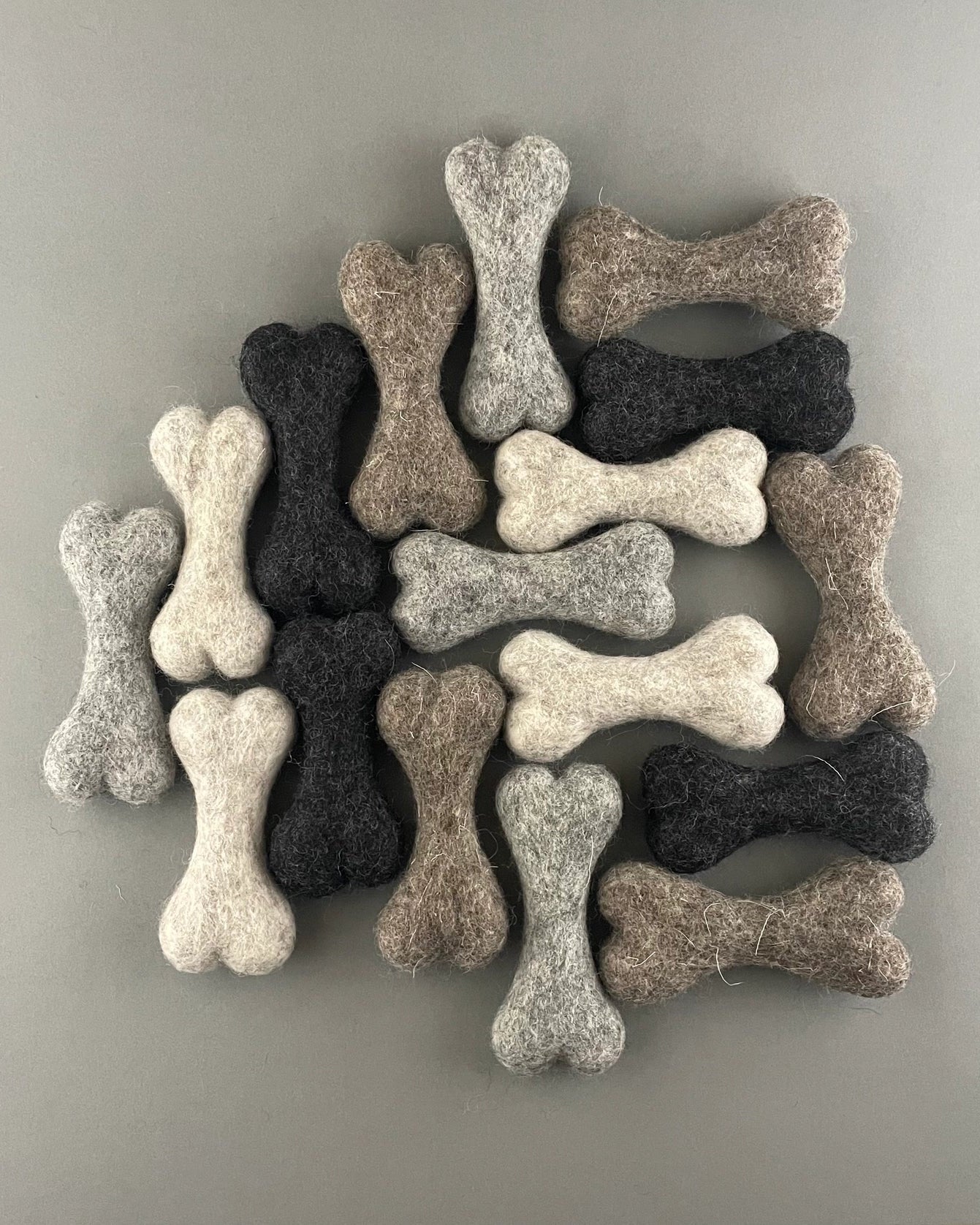 Set of bone-shaped dog toys in various colors on a gray background